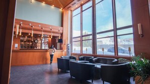 A lobby with a reception desk, seating area, and large windows offering a view of the outside.