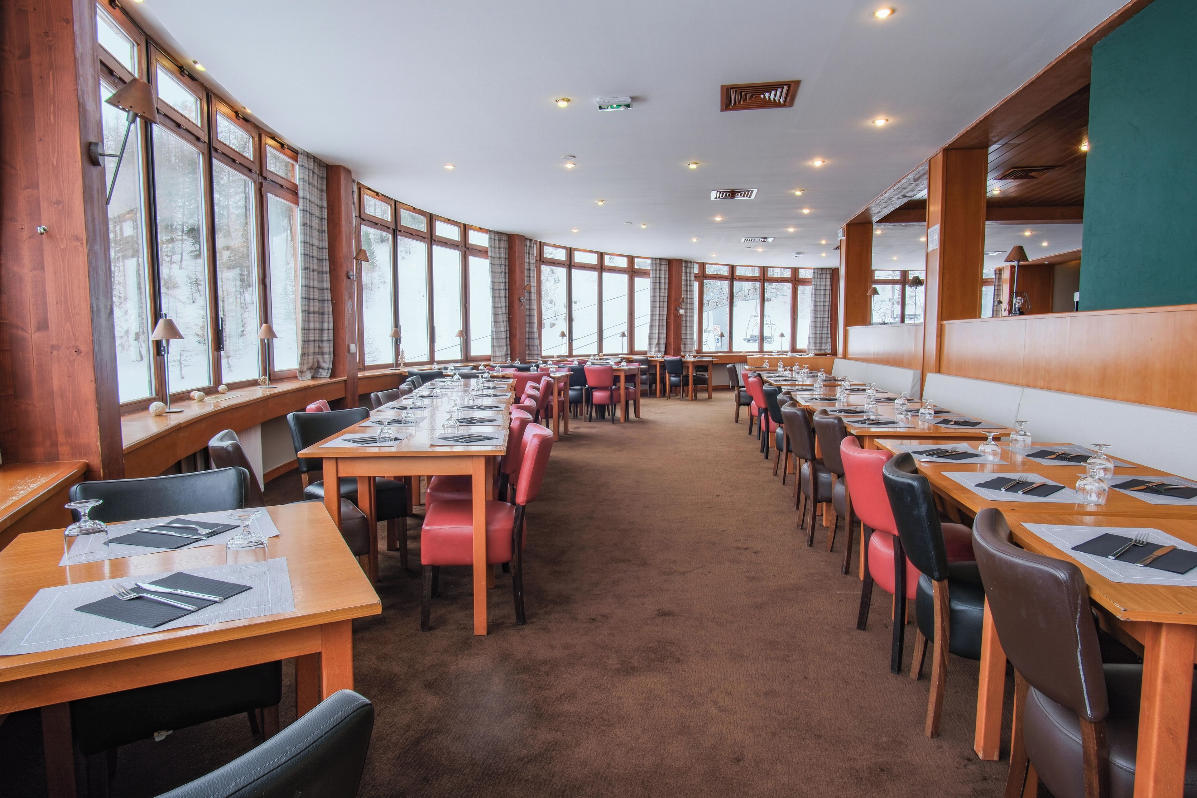 Un restaurant avec de longues tables, des chaises et de grandes fenêtres.