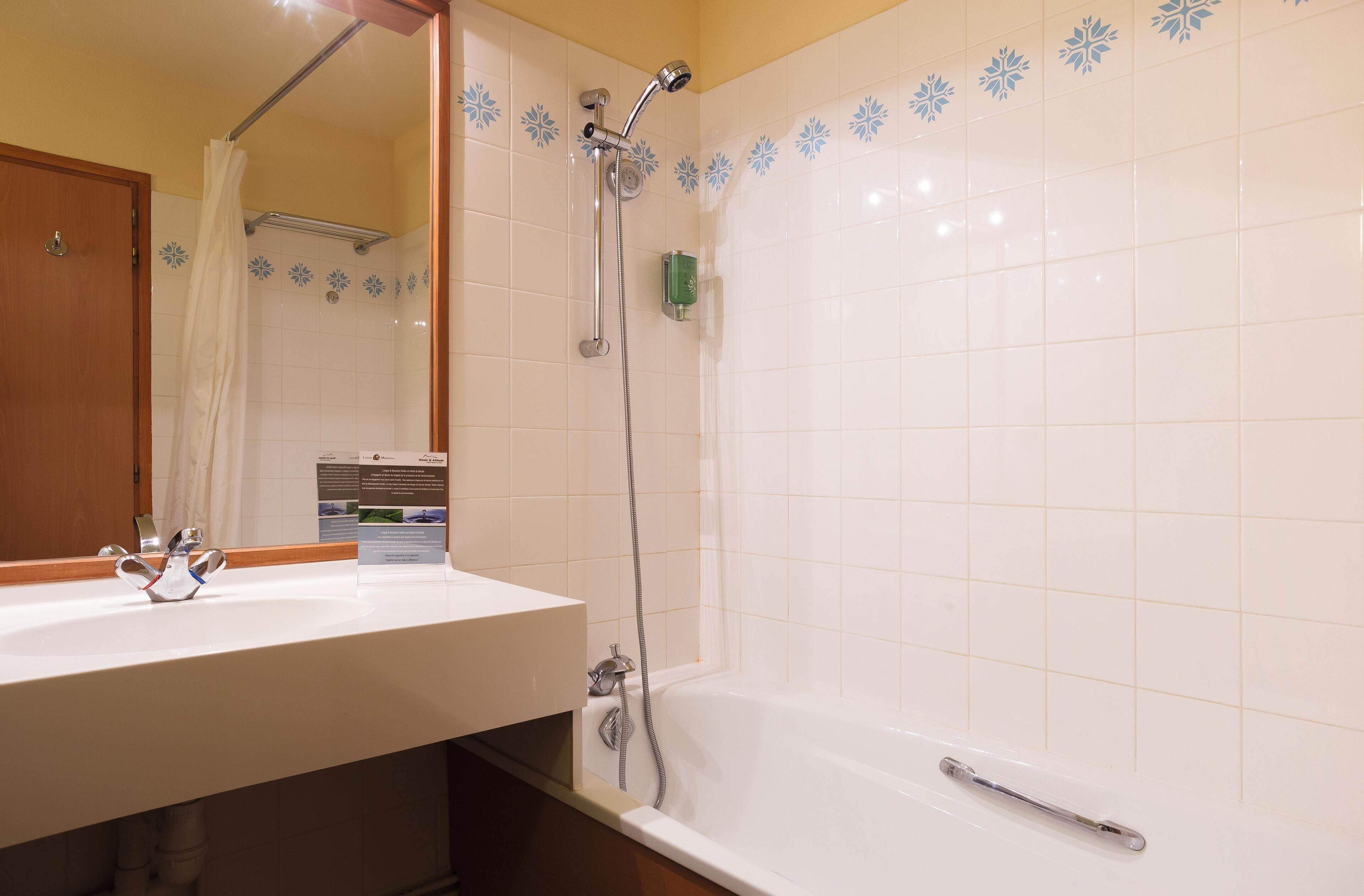 A bathroom with a white sink, a mirror, a shower with a handheld showerhead, and a bathtub.