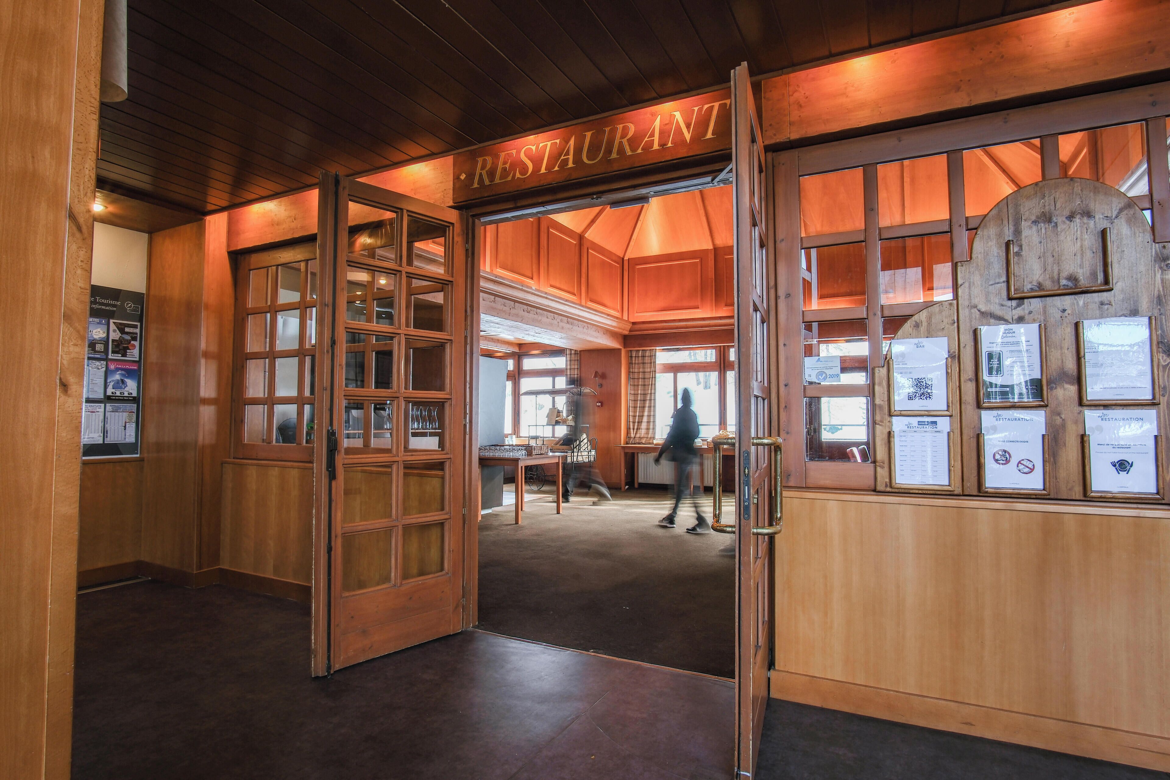 Un intérieur en bois avec une enseigne indiquant « RESTAURANT » et une personne qui entre.