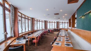 A conference room with long tables and chairs, large windows, and wooden paneling.
