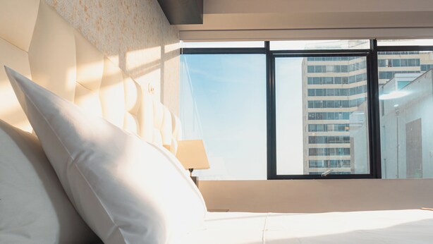 Una habitación de hotel con una cama grande, una mesita de noche y una ventana con vistas a un edificio.