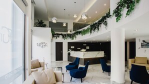 A modern lobby with a reception desk, seating area, and a glass coffee table.