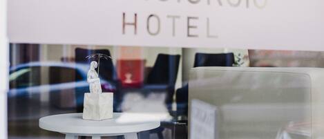 A hotel sign reading "FRANGIORGIO HOTEL" with a small table and a statue in the foreground.