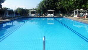 Une piscine d’un bleu éclatant, dotée de chaises longues et de petits kiosques.