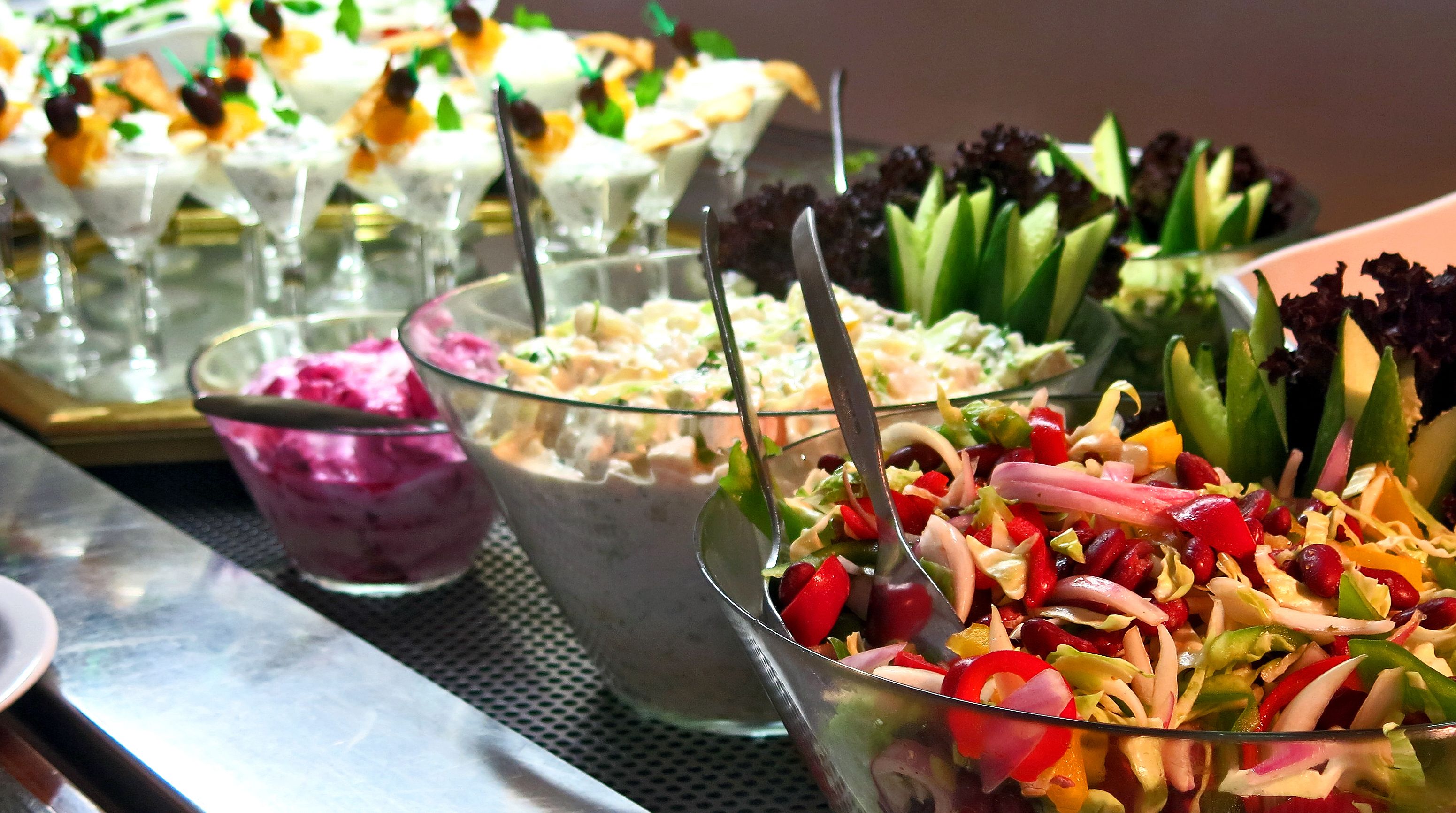 A buffet table with various dishes including salads, desserts, and a dessert bar.