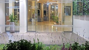 Un hall d’entrée moderne avec des portes en verre, des plantes d’intérieur et des espaces aménagés pour s’asseoir.