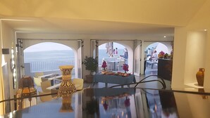 Un comedor con vista al mar, una mesa con un florero y una planta en maceta.