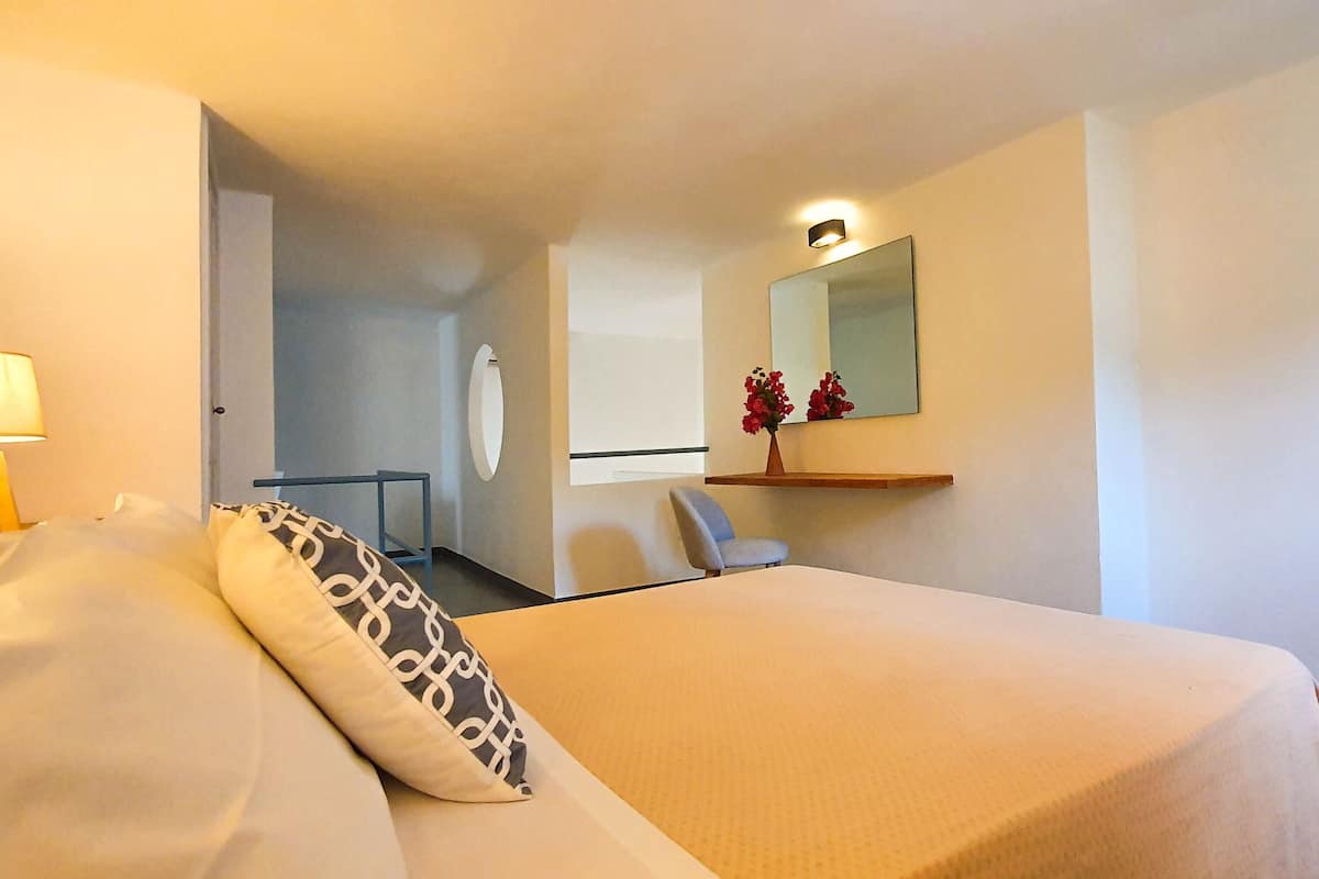 Een hotelkamer met een bed, een bureau, een stoel, een lamp en een spiegel.