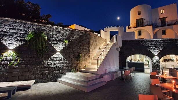 Un espacio al aire libre con paredes de piedra y una escalera que lleva a un restaurante.