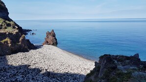 Una costa rocosa con una formación rocosa destacada y una playa de guijarros.
