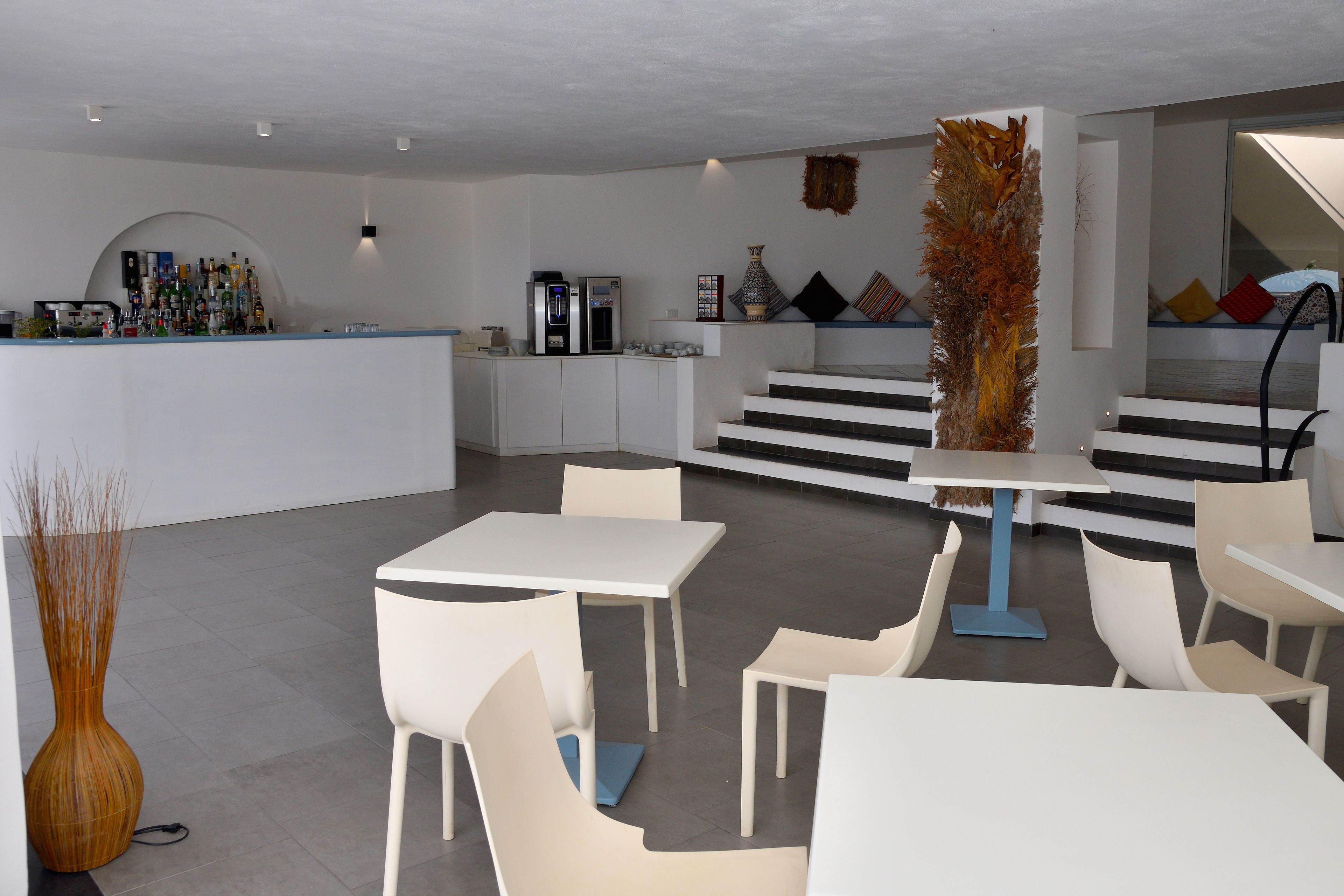 Ein modernes Interieur mit Barbereich, weißen Möbeln und einer Treppe, die zu einem Schlafboden führt.