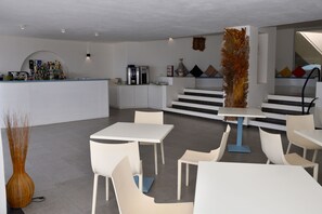 Un intérieur moderne avec un espace bar, des meubles blancs et un escalier menant à une mezzanine.