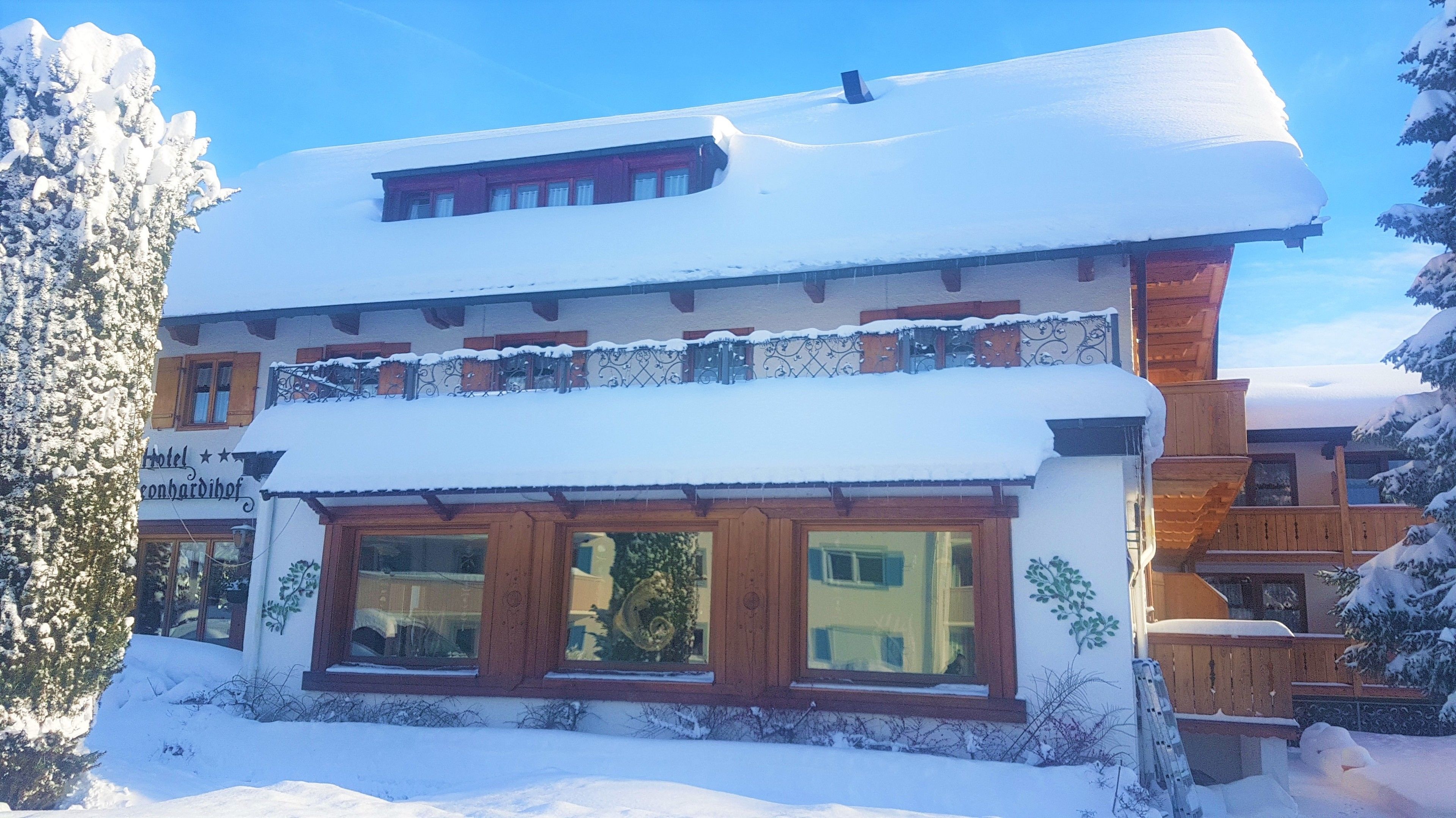 Um hotel de dois andares com telhado coberto de neve e fachada de madeira.