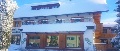 Um hotel de dois andares com telhado coberto de neve e fachada de madeira.