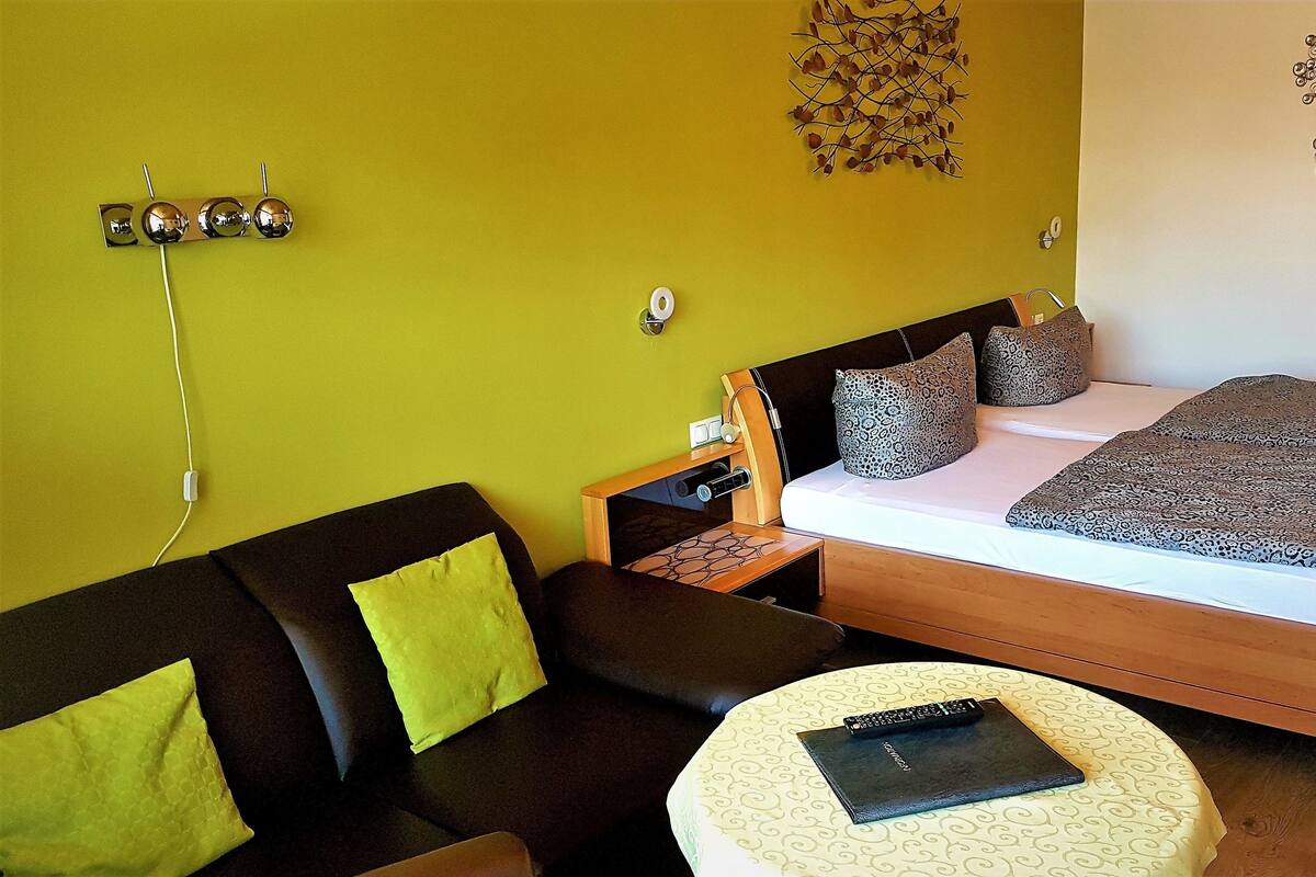 A bedroom with a bed, bedside table, lamp, and a small round table with a book.