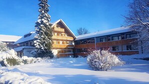 Un edificio de madera de varios pisos con balcones, rodeado de nieve en el suelo y entre los árboles.