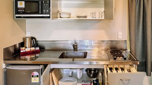 Una cocina compacta con microondas integrado, un lavabo y un refrigerador pequeño.
