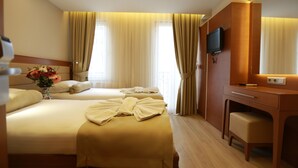 Une chambre d’hôtel avec deux lits, un bureau, une télévision et un vase de fleurs.