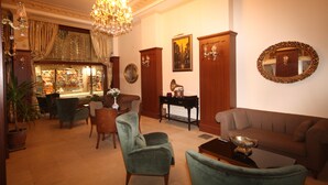 Un salon spacieux agrémenté d’un lustre, d’un canapé, de fauteuils et d’une table basse.