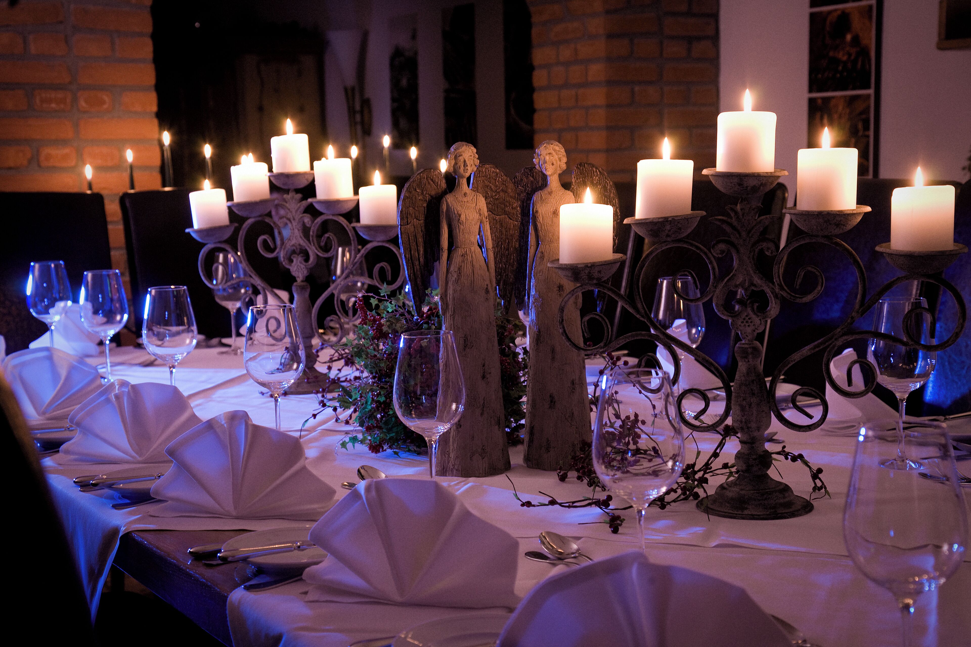 Een gedekte tafel voor een formeel diner, met meerdere kaarsen, glazen en een decoratief middelpunt.