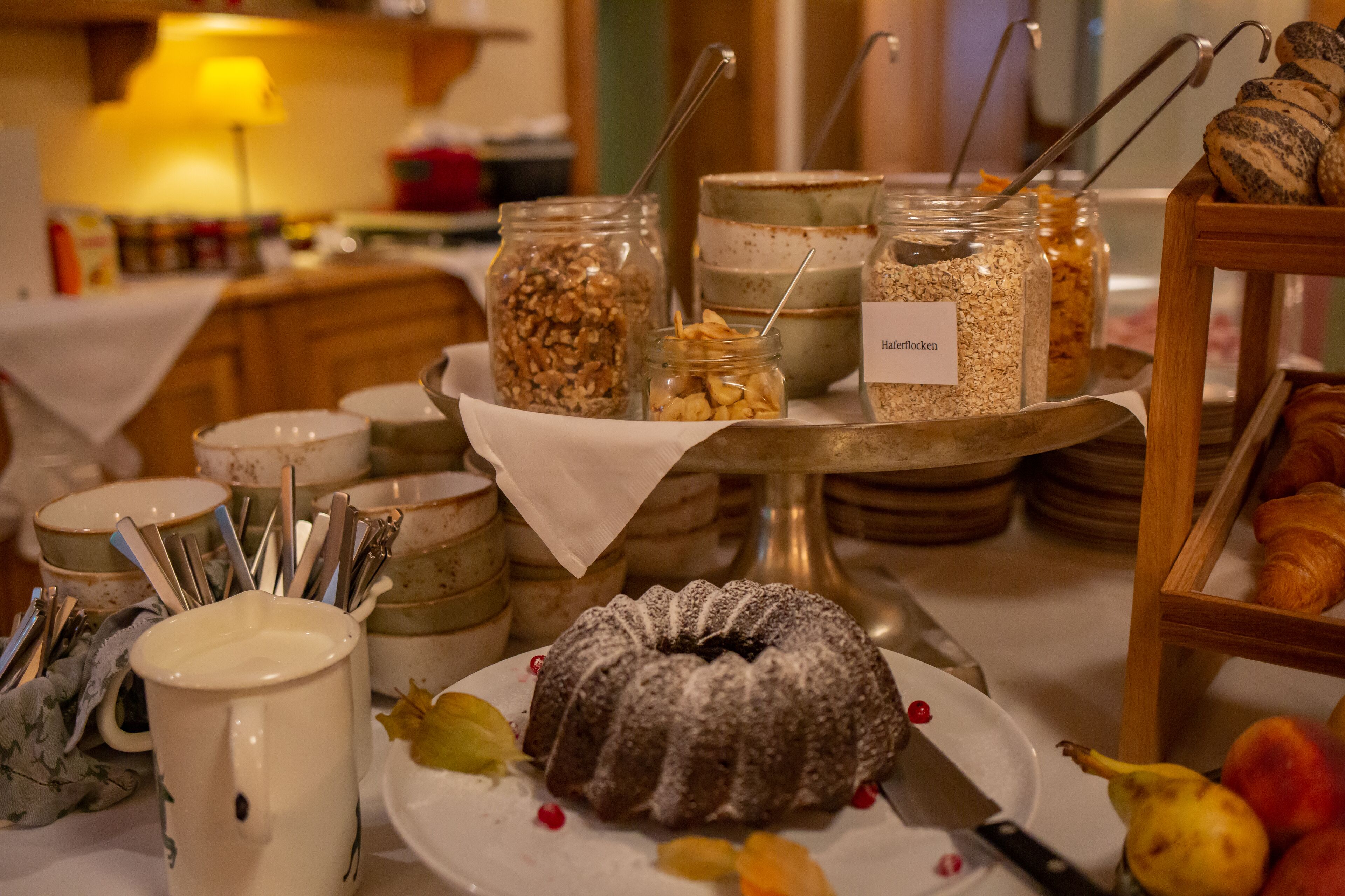 A buffet with various food items, including a bundt cake, fruits, and granola.