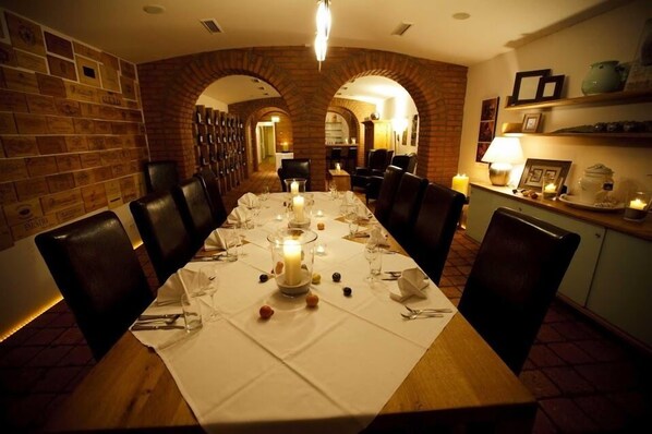 Un comedor con una mesa larga dispuesta para una comida, rodeado de paredes y arcos de ladrillo.