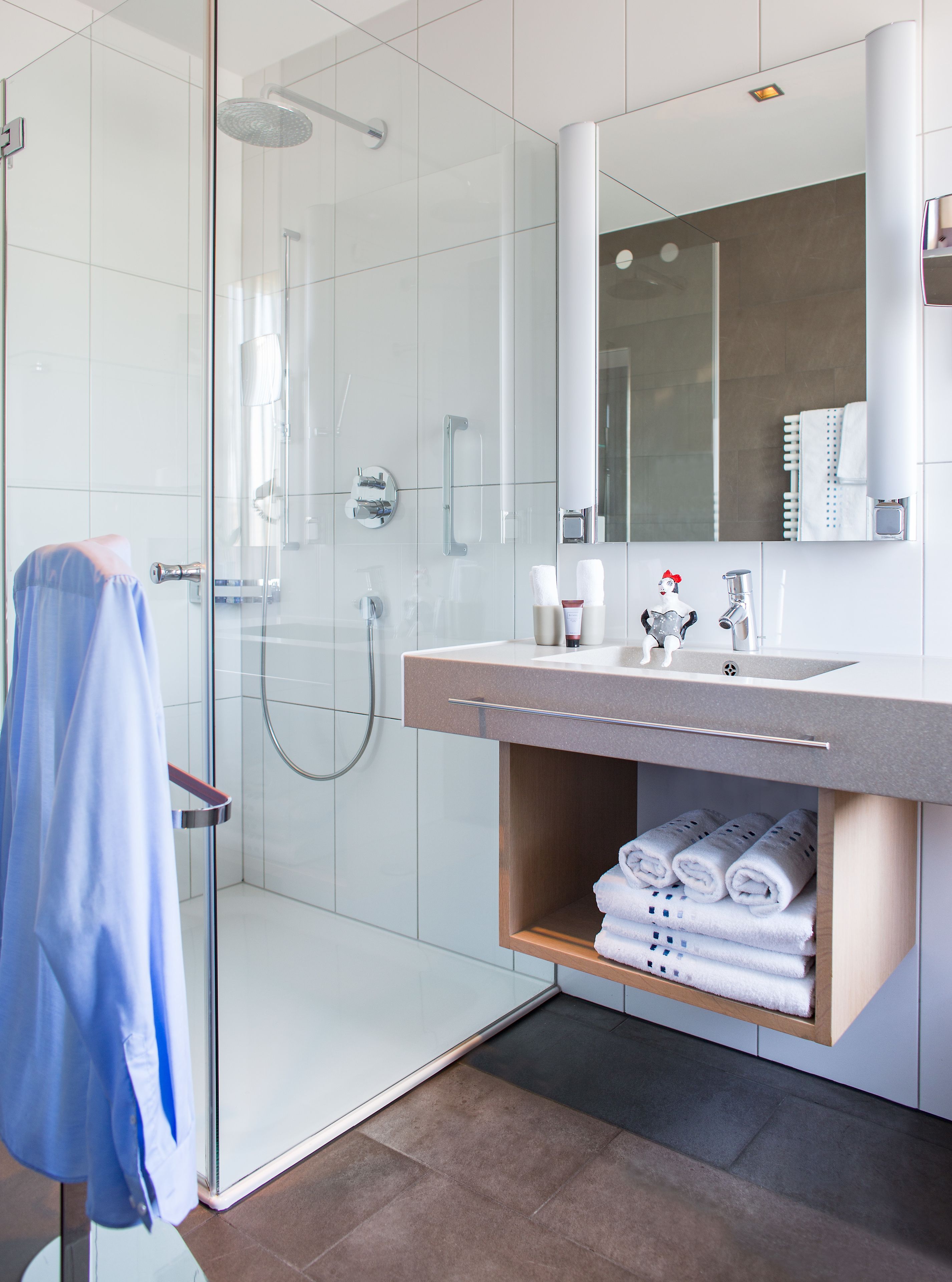 Een moderne badkamer met een douche met glazen wand, een wastafelmeubel en een handdoekrek.