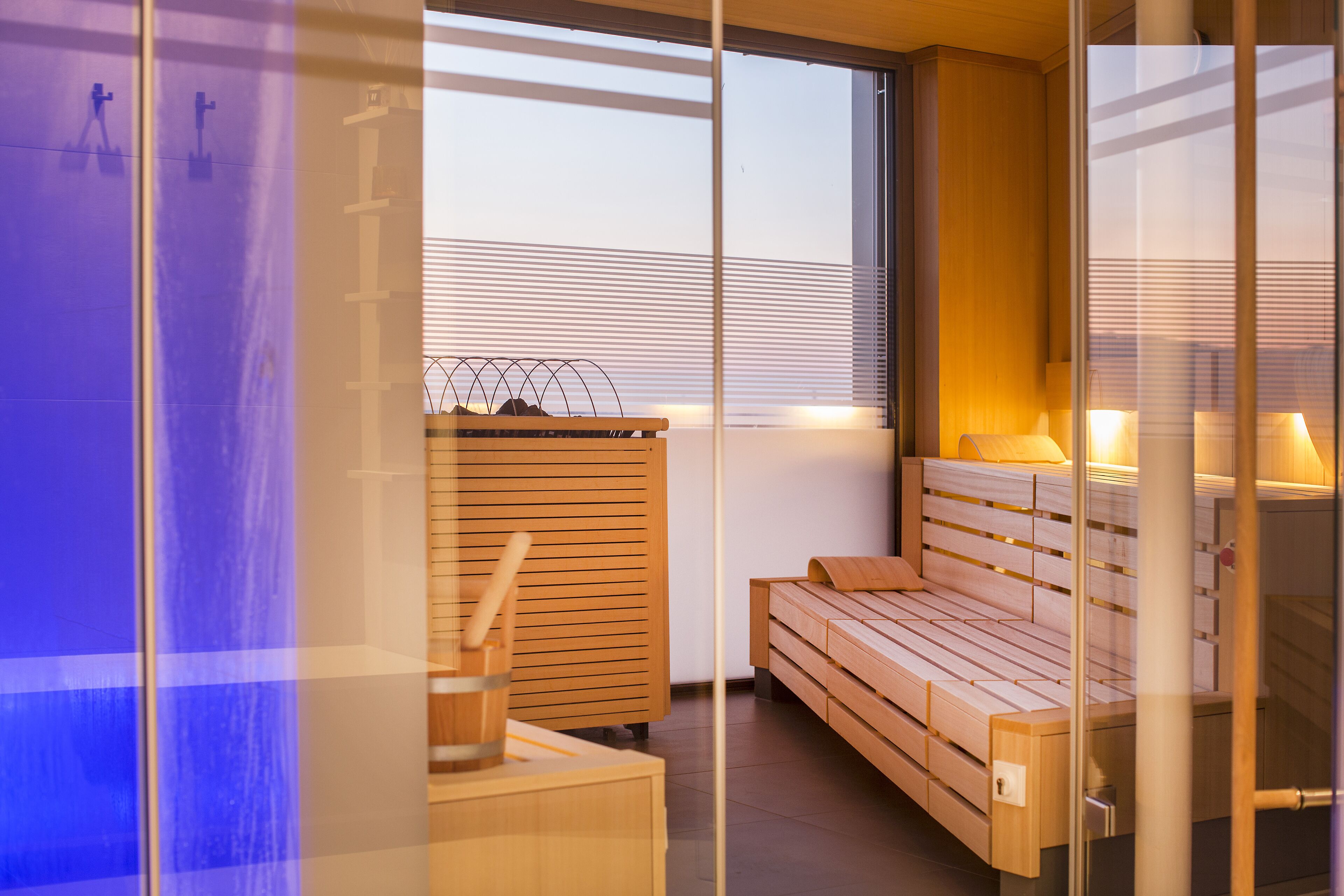 Una habitación moderna y bien iluminada con un banco de madera, una mesita y una ventana con persianas.