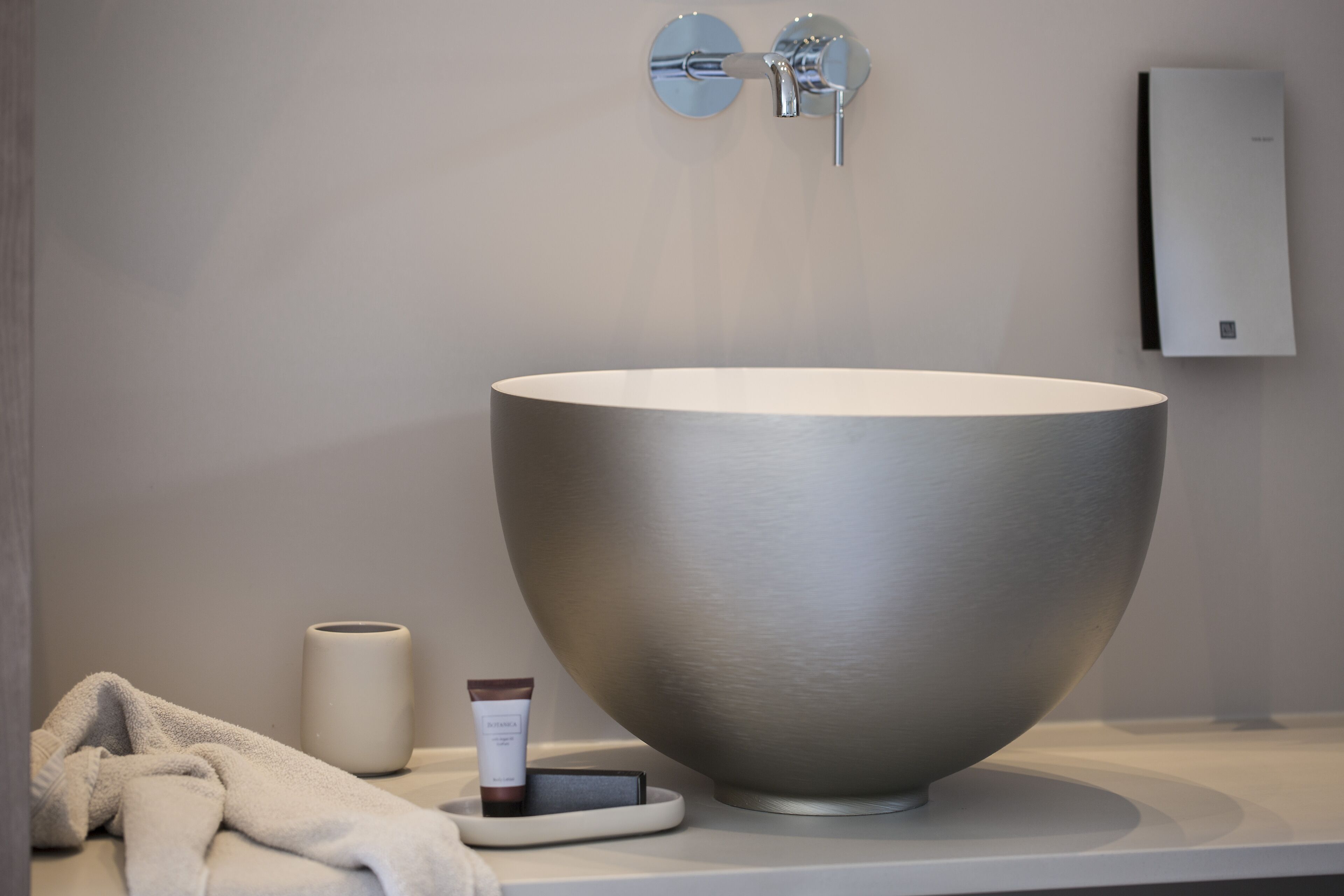 Un baño moderno con un lavabo grande de forma redondeada, una toalla y un dispensador de jabón.