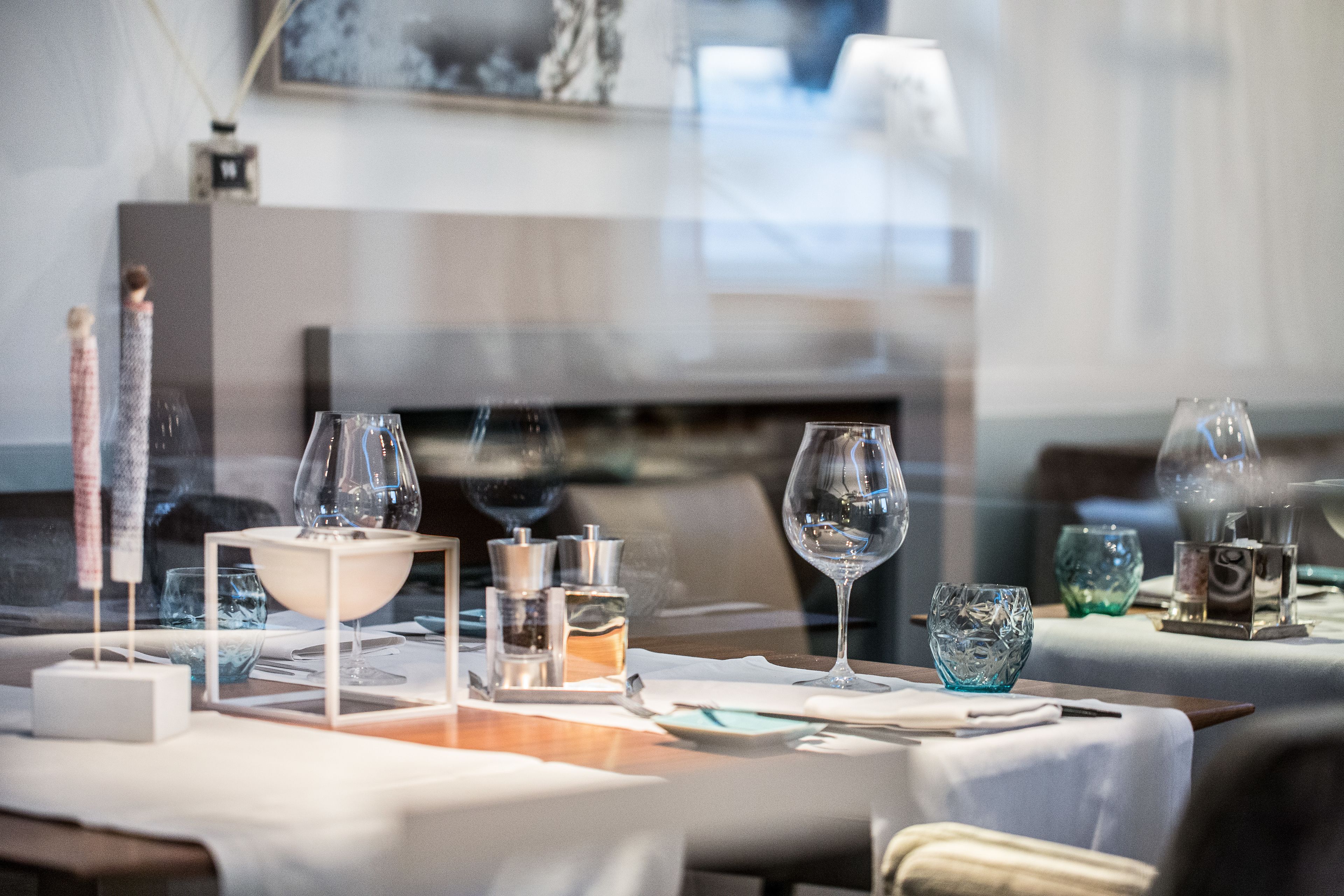 A dining table set with wine glasses, a bowl, and a candle.