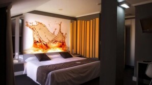Una habitación de hotel moderna con una cama grande, un televisor montado en la pared y una obra de arte original.