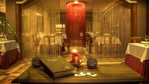 Un restaurante con un ambiente cálido e íntimo, que cuenta con una vela central, un libro y objetos decorativos sobre una mesa.