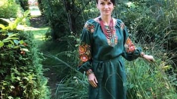 Una persona de pie en un jardín con abundante follaje y un sendero.