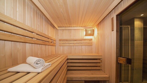 Una sauna de madera con bancos y un banco con toallas.