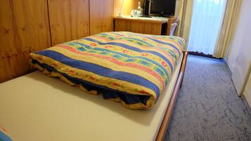 A bedroom with a bed, wooden wardrobe, desk, and a television.
