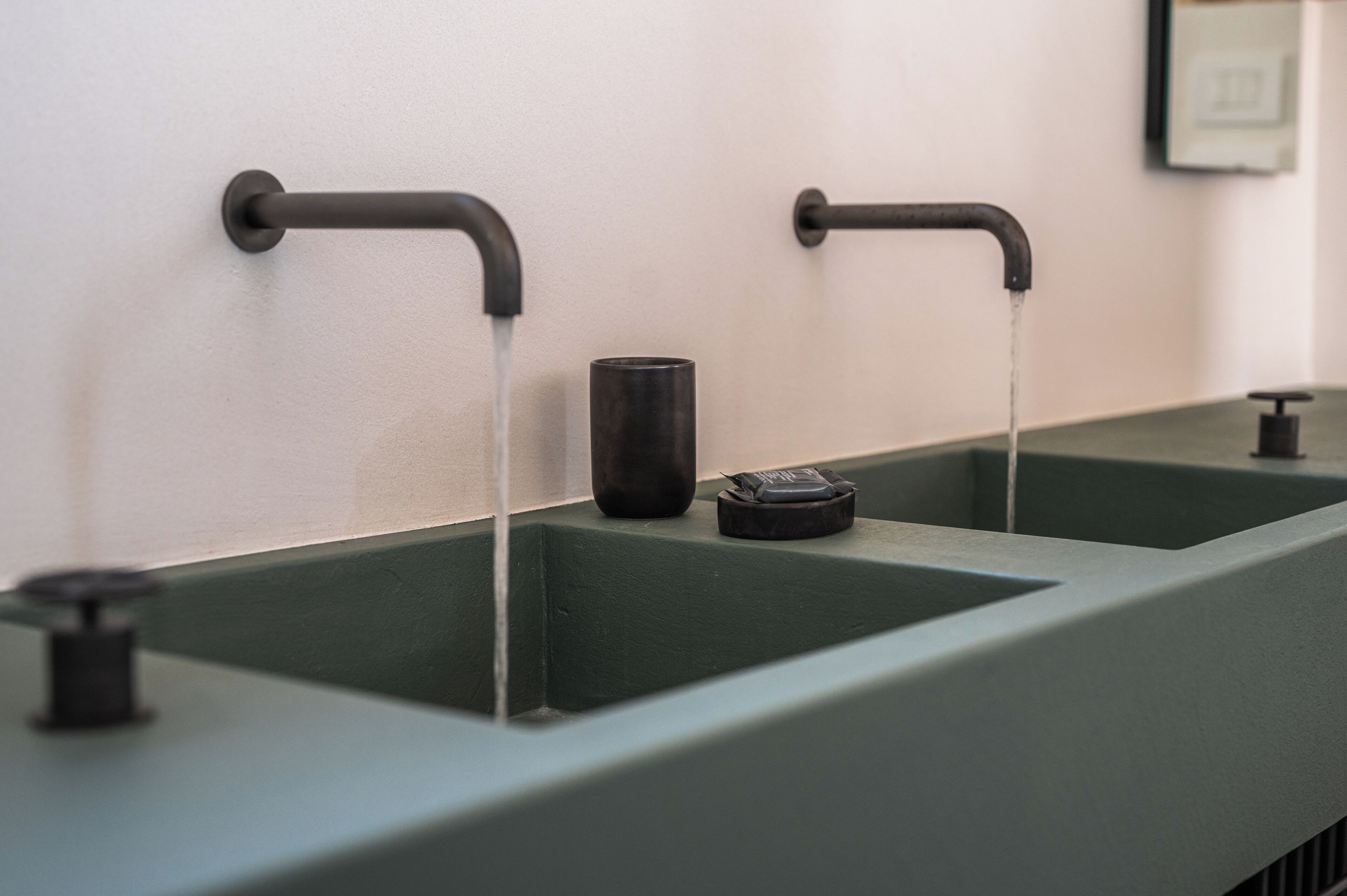 A modern bathroom with two sinks and faucets.