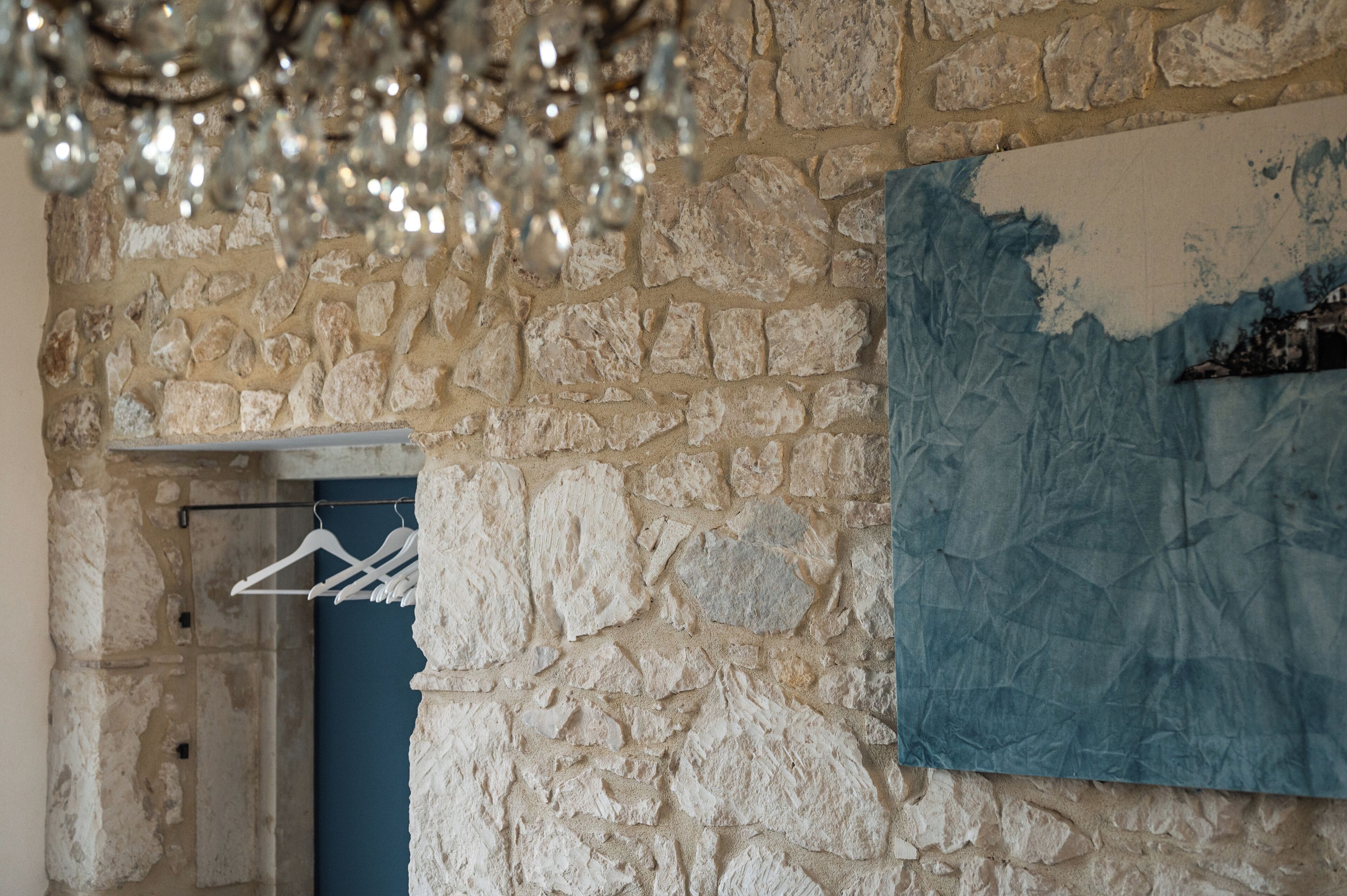 A stone wall with a crumpled blue paper, a white hanger, and a partially visible door.