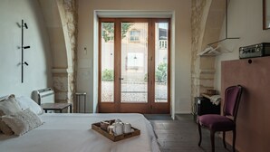 Une chambre à coucher avec un lit, une chaise, une petite table et une valise.