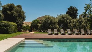 Une piscine à l’eau claire, entourée d’une terrasse en bois et de plusieurs chaises longues.