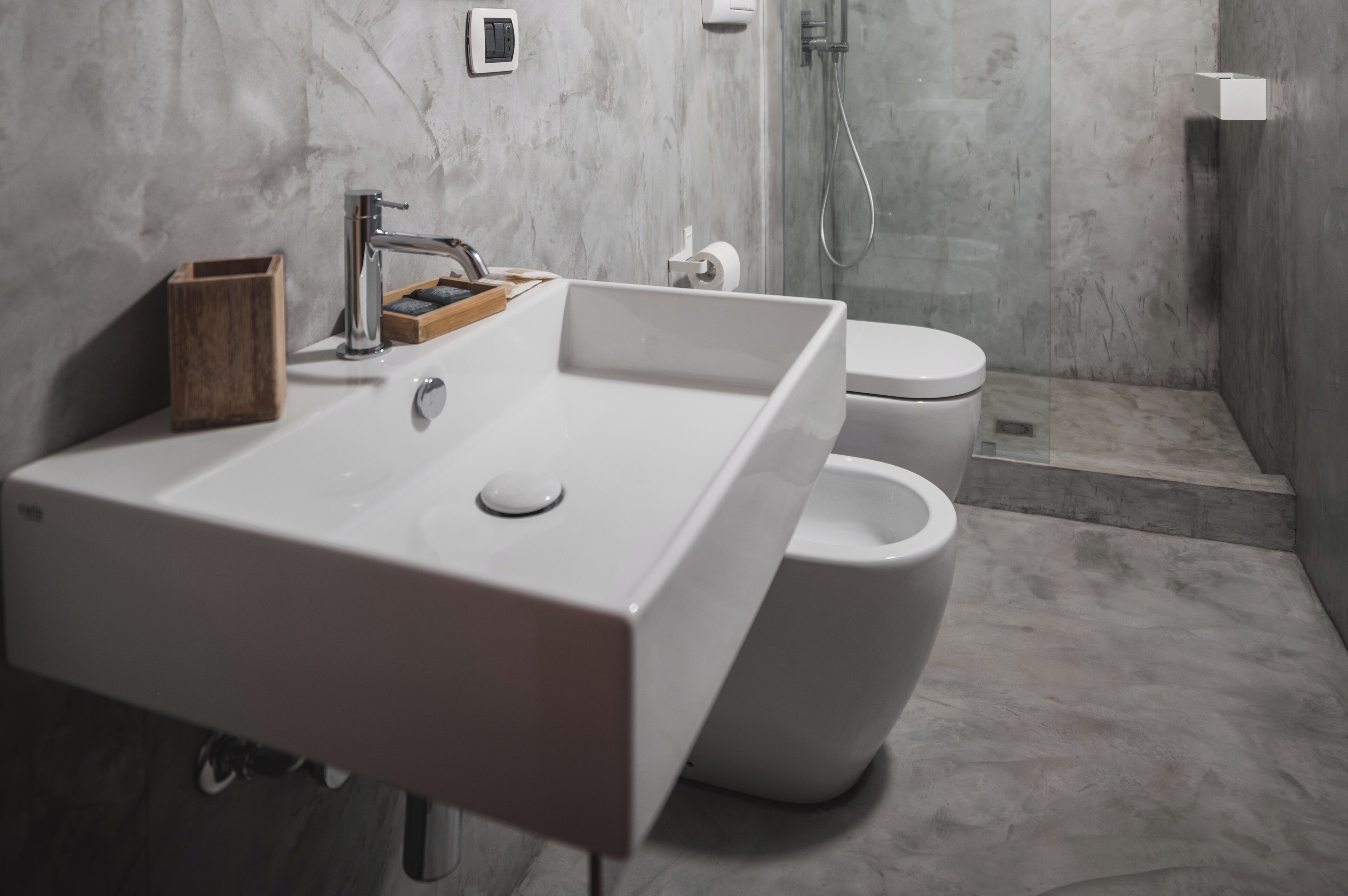 Un bagno moderno con un lavandino bianco ampio, un WC e uno spazio doccia.