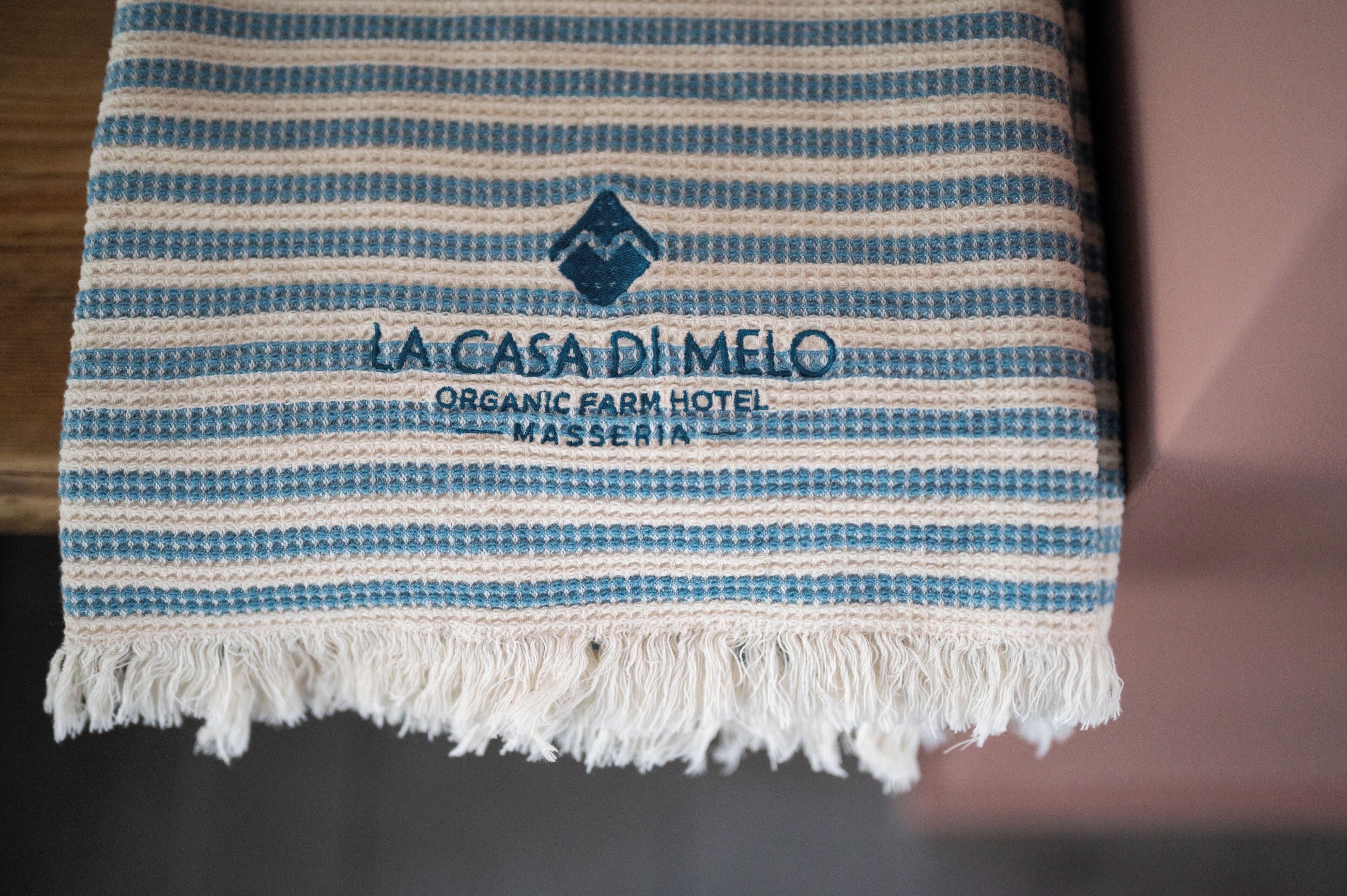 Eine gestreifte Decke mit dem Aufdruck 'La Casa Di MeLo Organic Farm Hotel Masseria'.
