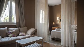 A bedroom with a bed, a bedside table, a nightstand, and a window with curtains.
