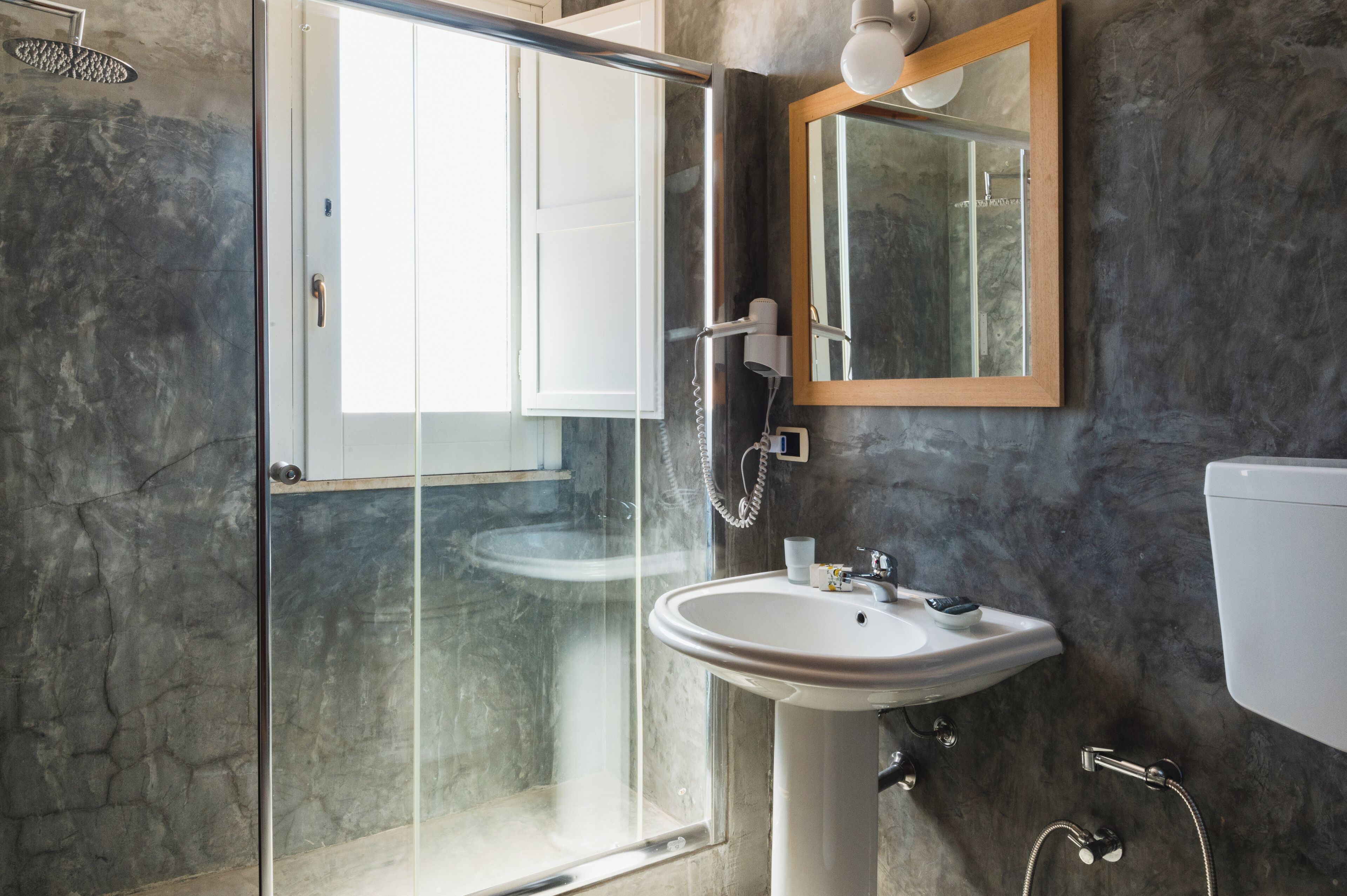 Un baño moderno con cabina de ducha de vidrio, un lavabo e inodoro.