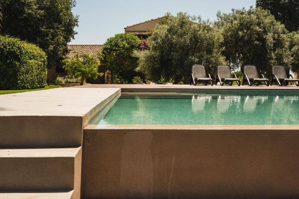 A swimming pool with lounge chairs and a building in the background.