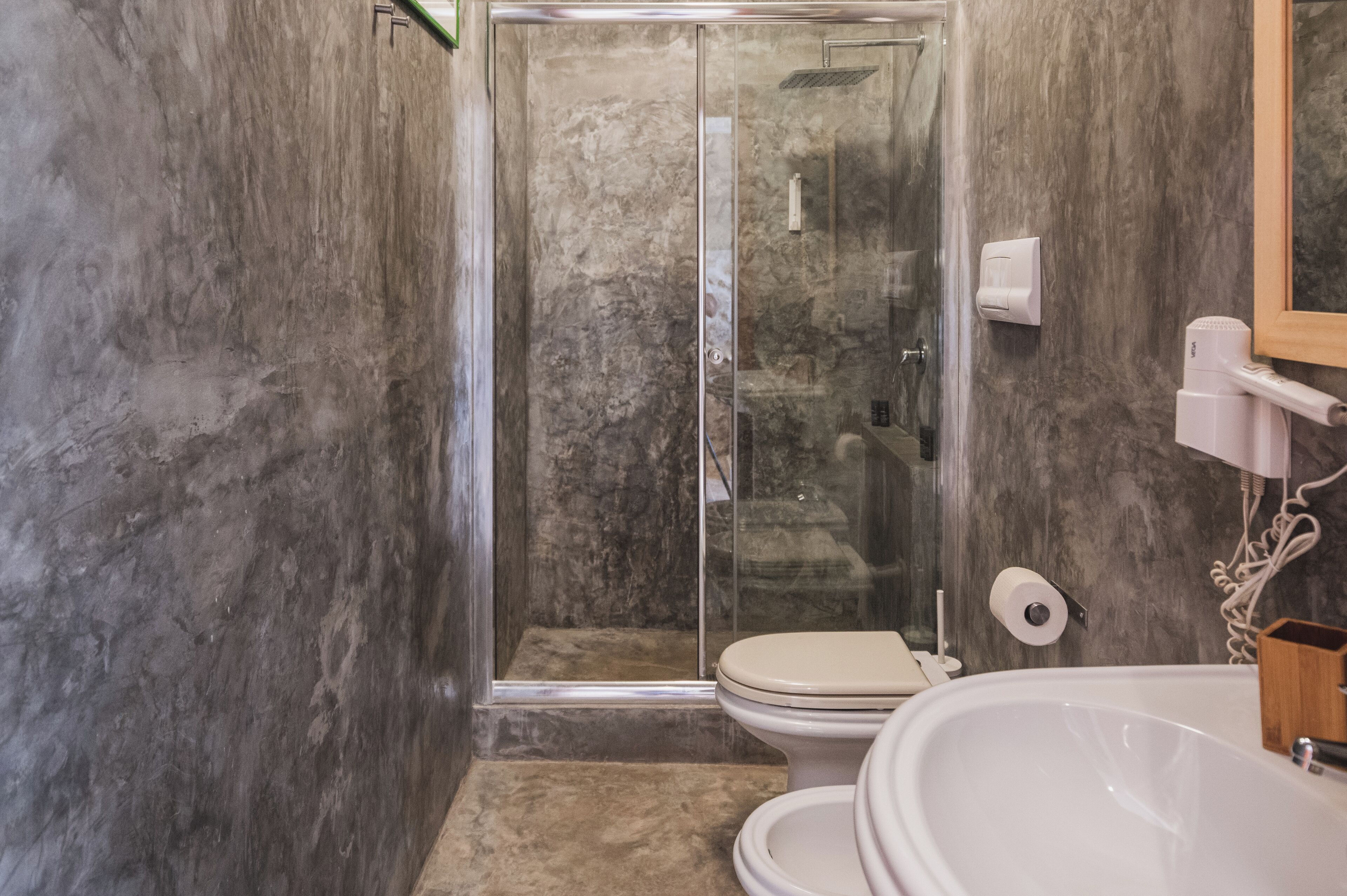 A bathroom with a glass-enclosed shower, a toilet, and a sink.