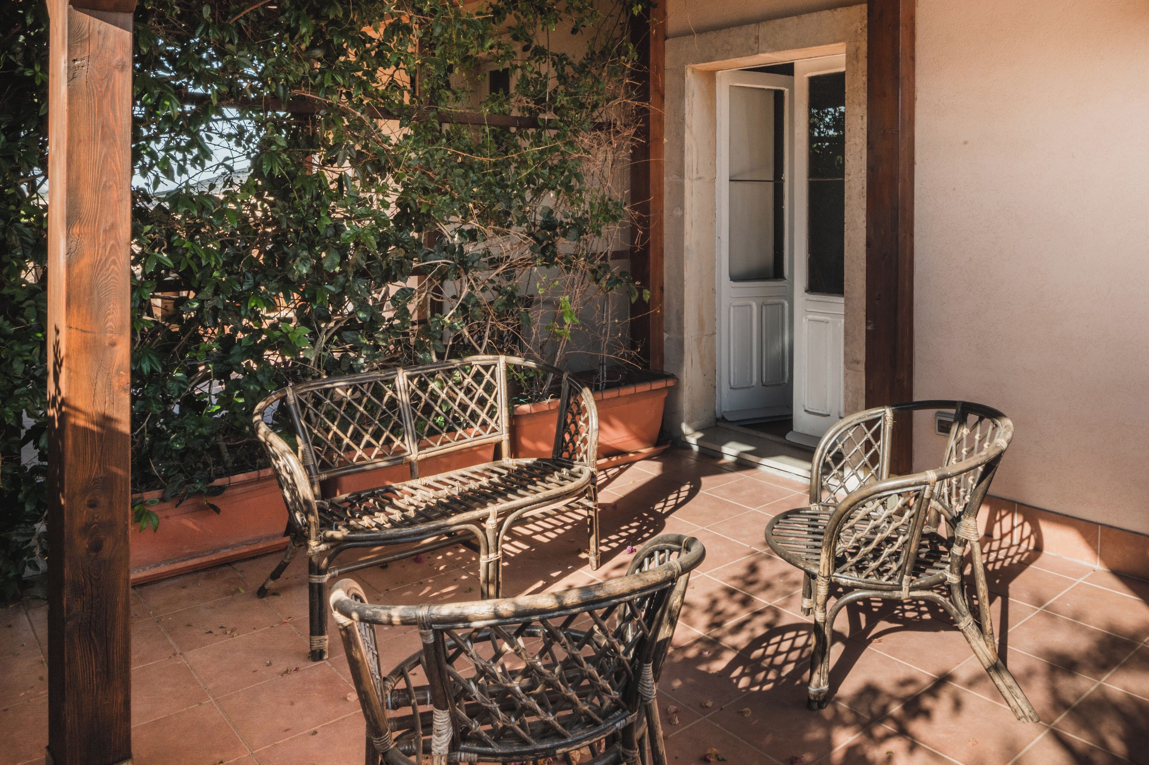 Un patio con mobiliario de mimbre y plantas en macetas.