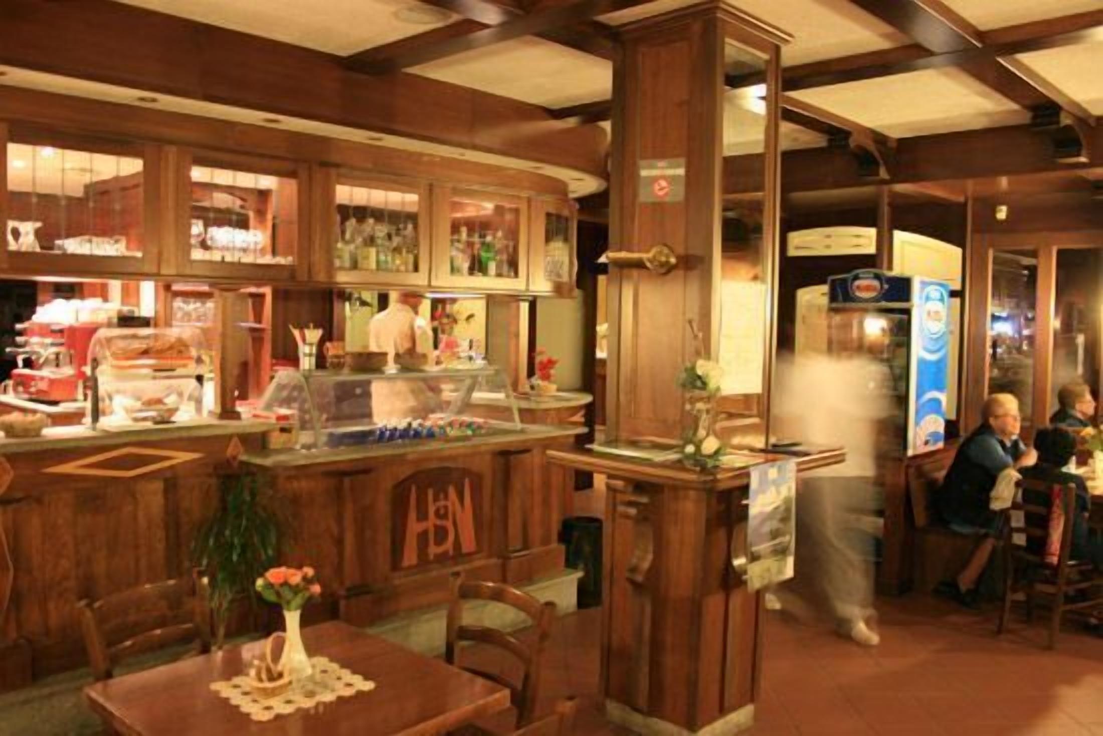 A restaurant interior with wooden furniture, a counter with a beverage dispenser, and a table with a vase.