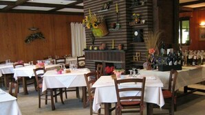 A restaurant with multiple tables and chairs, a bar area with bottles, and a decorative wall with various items. - Saint Nicolas (Saint-Nicolas)