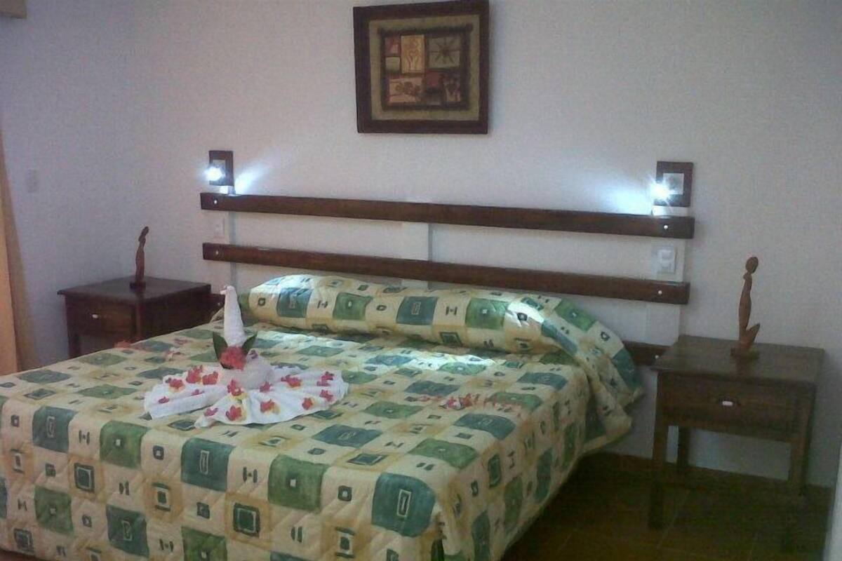 A neatly made bed with a patterned bedspread, two bedside tables with decorative items, and a framed picture on the wall.